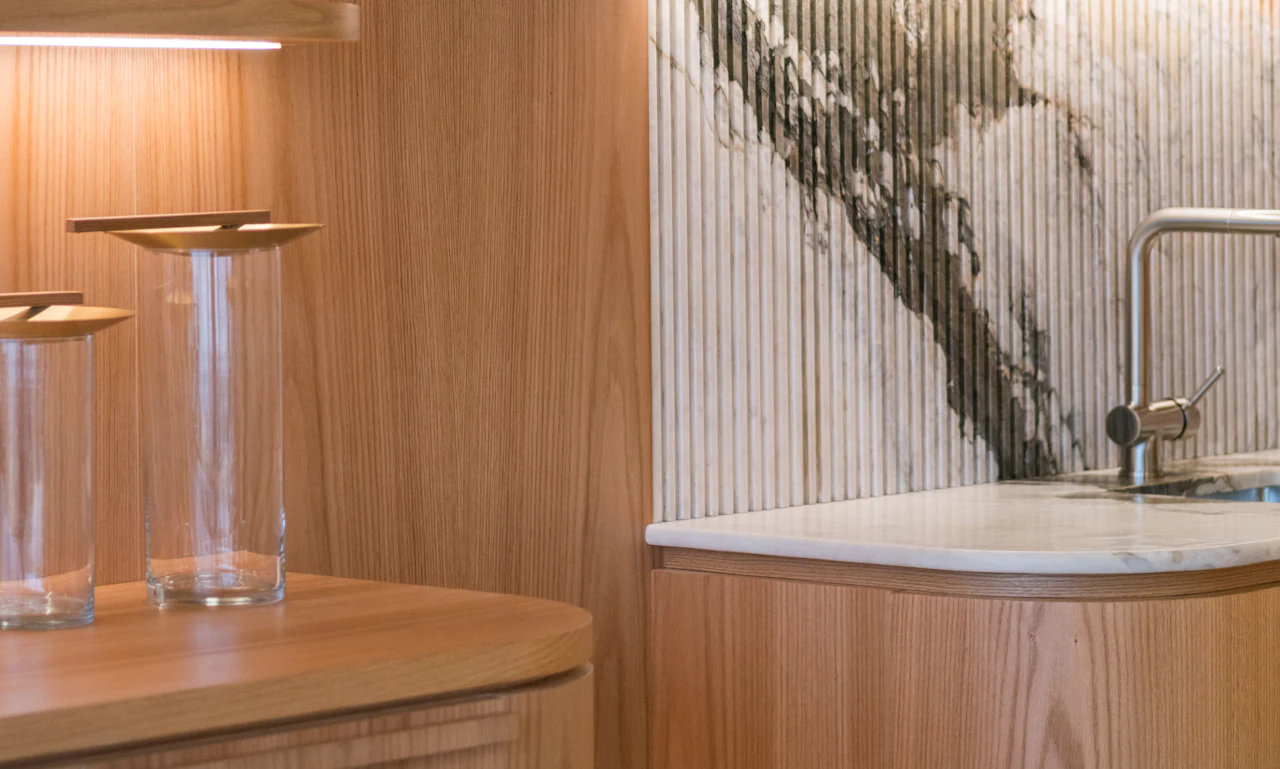 A curved timber kitchen bench beneath a fluted marble splashback