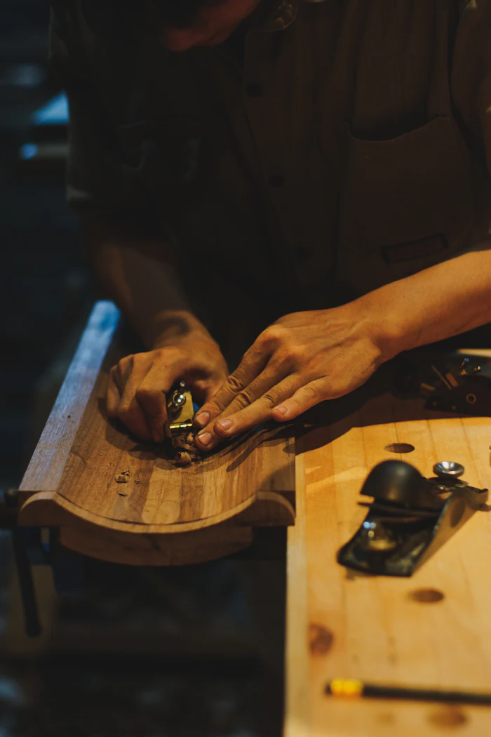 A joiner's hands guiding a hand plane along a length of timber